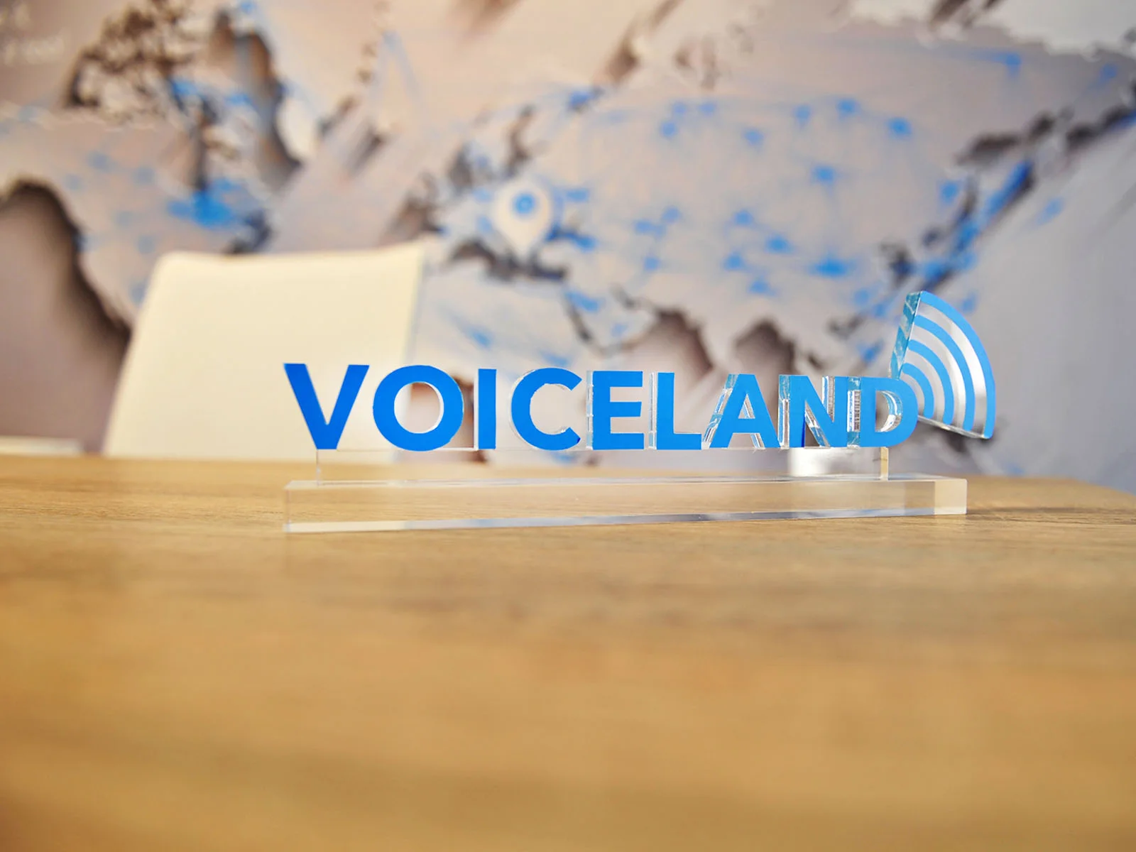Blue Voiceland logo on a transparent acrylic desk sign