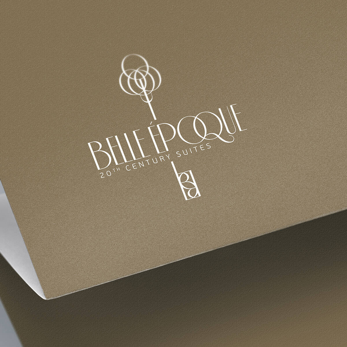 White Belle Époque 20th Century Suites logo on folded gold paper