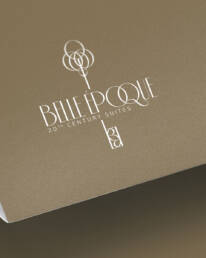 White Belle Époque 20th Century Suites logo on folded gold paper