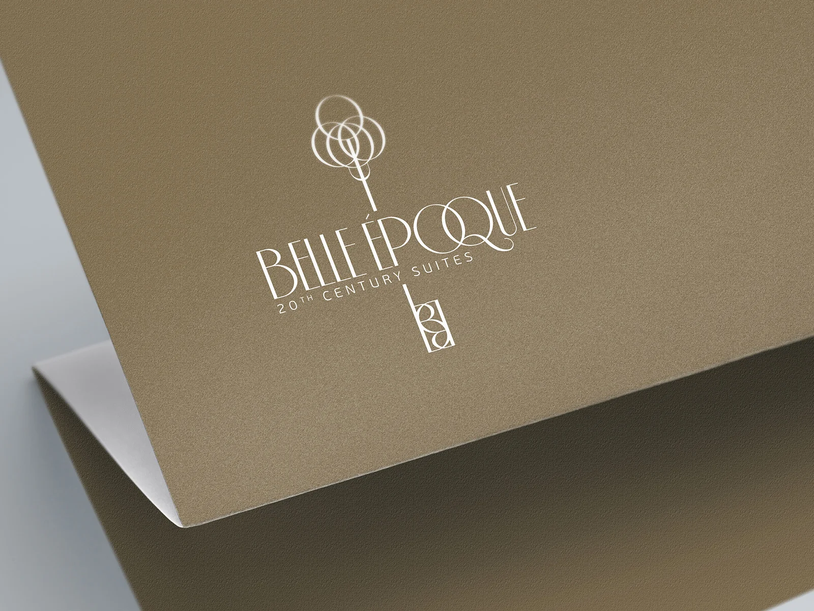 White Belle Époque 20th Century Suites logo on folded gold paper