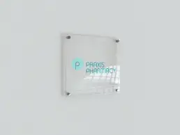 Praxis Pharmacy logo on a transparent acrylic sign mockup