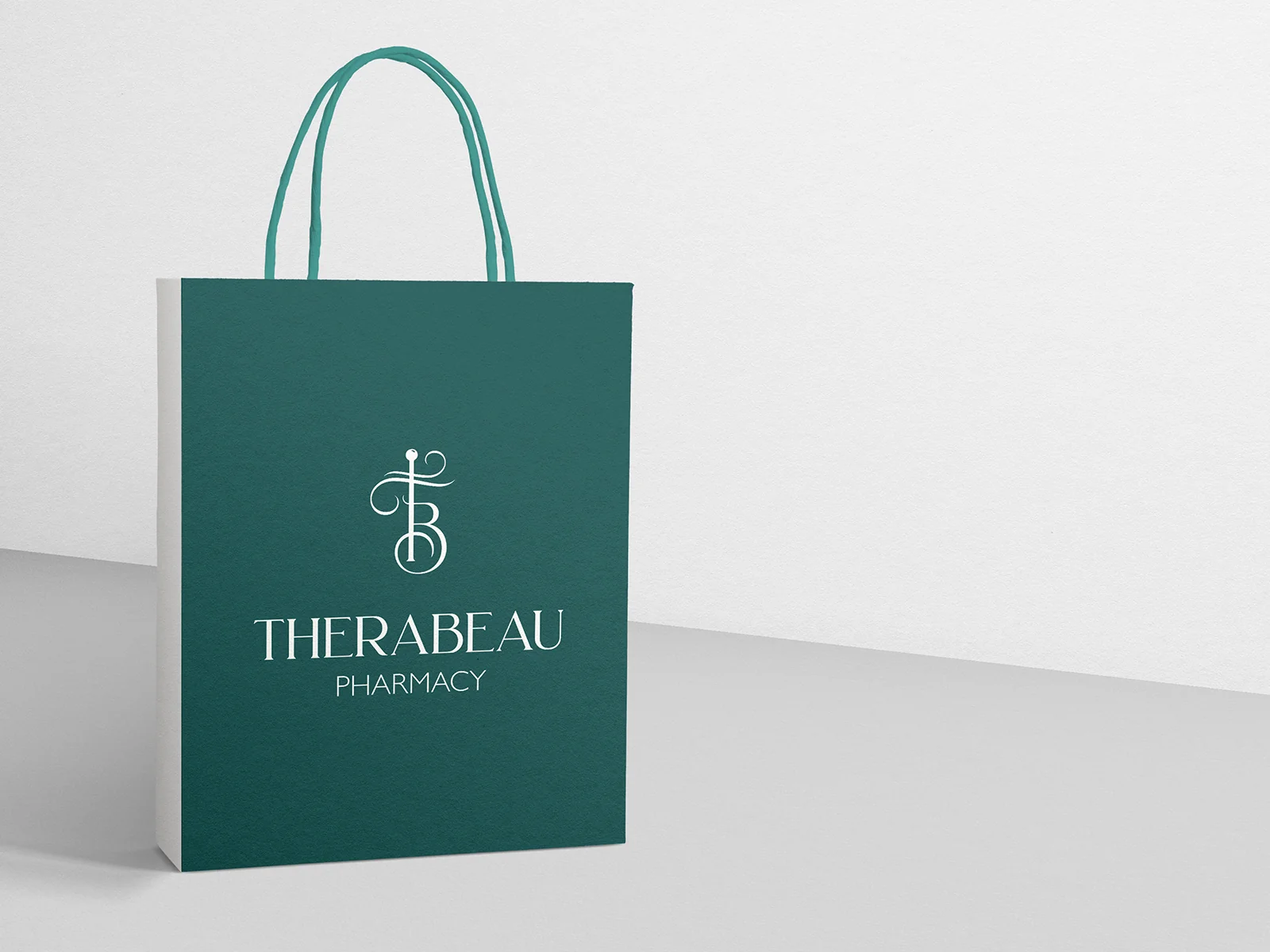 Χάρτινη τσάντα Therabeau Pharmacy σε βαθύ πράσινο με λευκό μονόγραμμα και λογότυπο