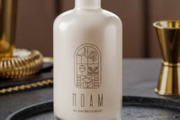 White NOAM bottle with a wooden stopper and gold logo