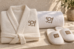507 Athens logo embroidered on an ivory robe and towel, with branded spa slippers