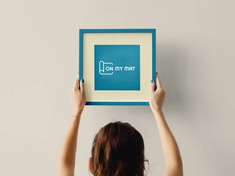 On My Mat Pilates Studio — framed brand identity held in hands