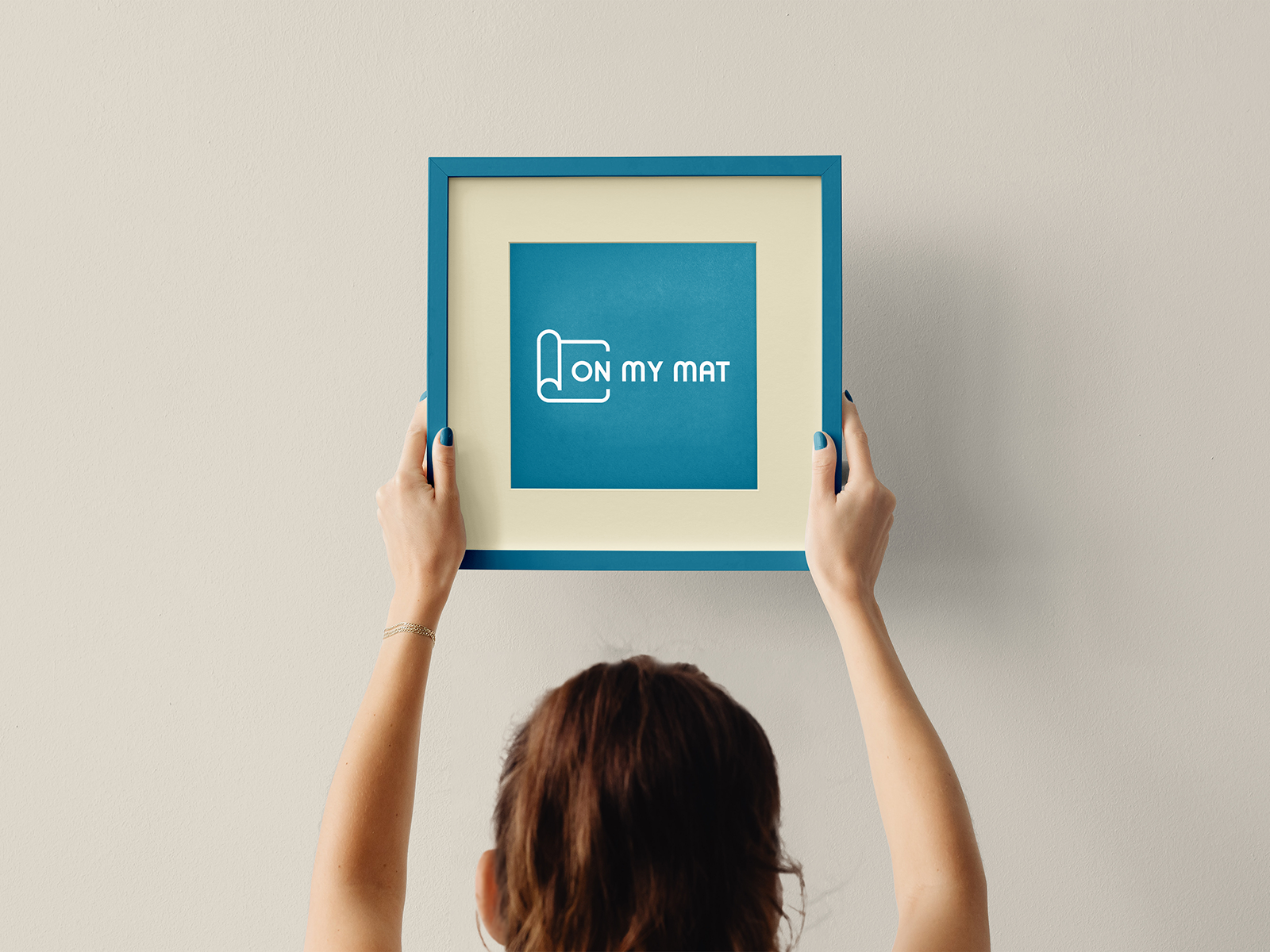 On My Mat Pilates Studio — framed brand identity held in hands