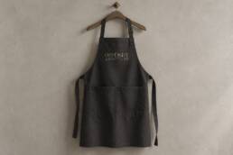 Charcoal restaurant apron mockup with an embroidered Opposite by Botrini at 507 logo