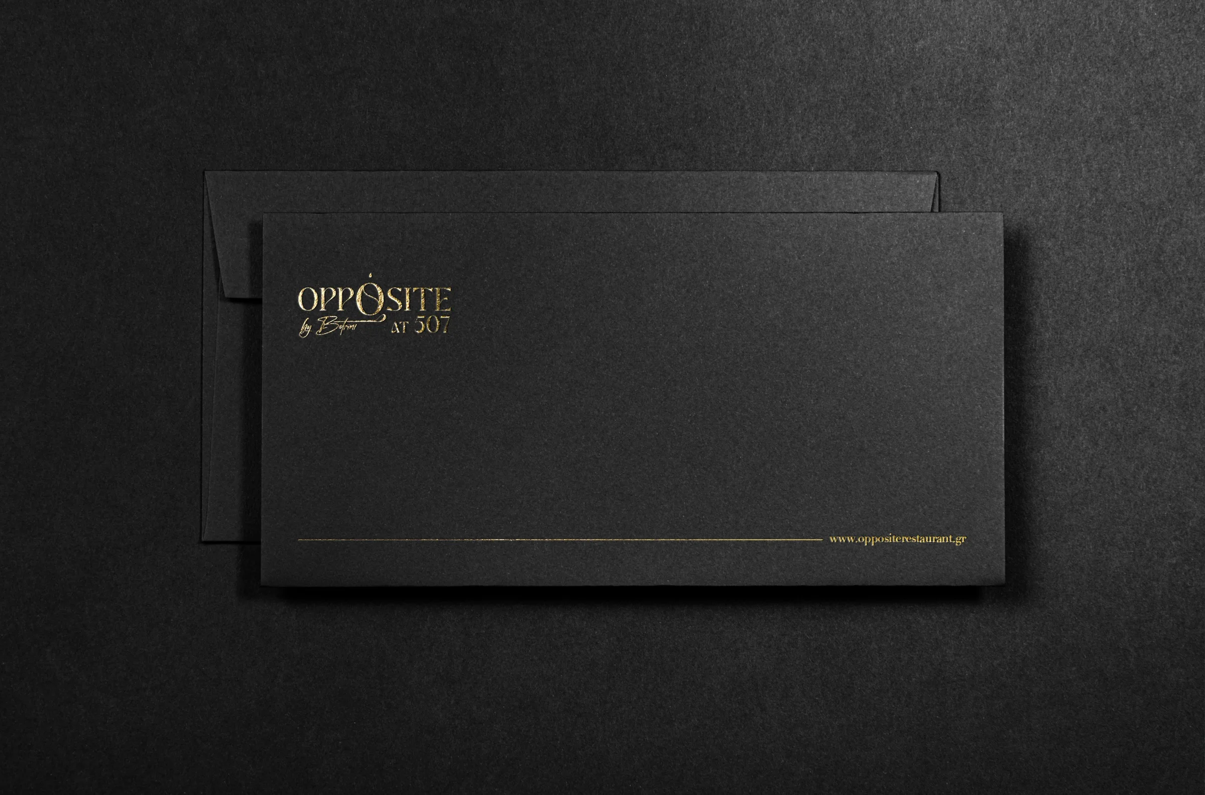 Charcoal envelope mockup with the gold Opposite logo