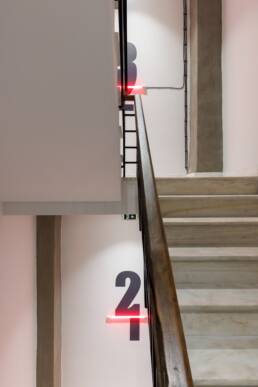 Floor wayfinding numbers with red light detail at Retroverse Hostel