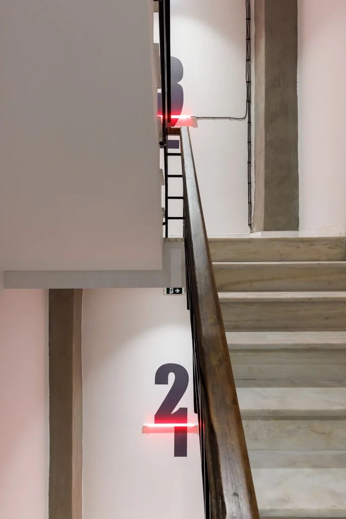 Floor numbering with a red lighting detail at Retroverse Hostel