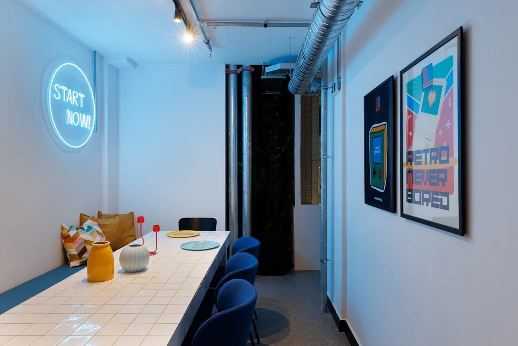 Retroverse posters and Start Now neon in a shared social space